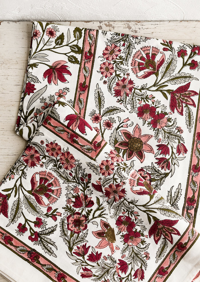 A block printed, floral patterned tablecloth in shades of pink and sage green.