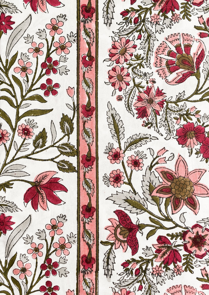 A block printed, floral patterned tablecloth in shades of pink and sage green.