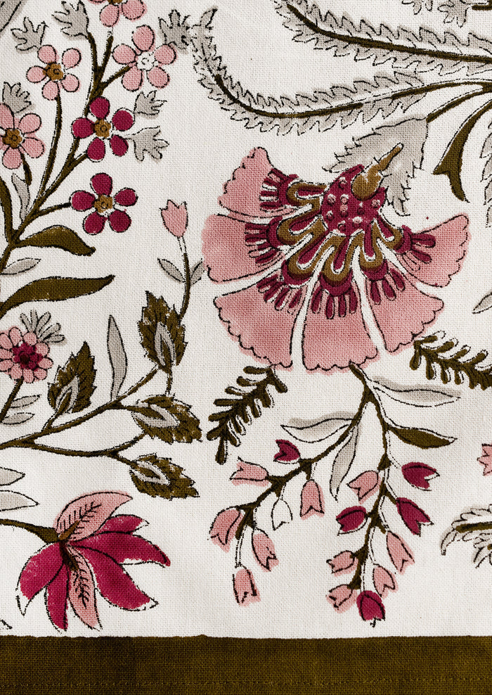 A cotton tea towel in block printed floral pattern in maroon, mauve and olive green.