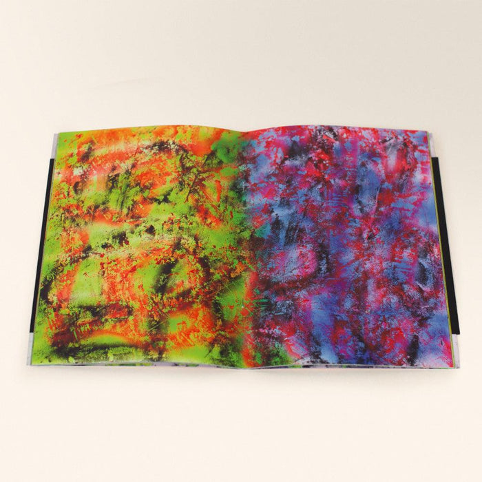 An open book displaying a vibrant abstract two-page spread with green orange red and blue colors