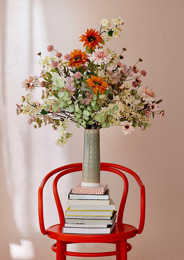 A faux flower arrangement with pink flowers and orange sunflowers.