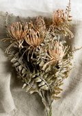 A faux floral spray in the form of blush colored pincushion flower.