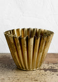 A pleated metal planter in distressed brass finish.