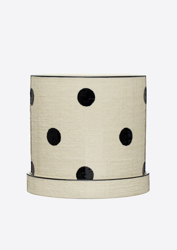 A polka dot ceramic planter in white with black dots, linen texture.