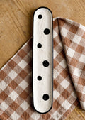 An oblong, skinny ceramic platter in cream with black polka dot print.