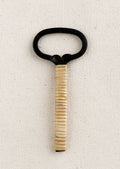 A black cast iron bottle opener with natural rattan wrapped handle.