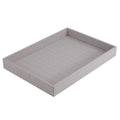 The Bodrum Wicker Rectangle Tray Grey is a light gray woven tray with raised edges and a textured design, shown angled against a white background. This serving tray has no visible handles.